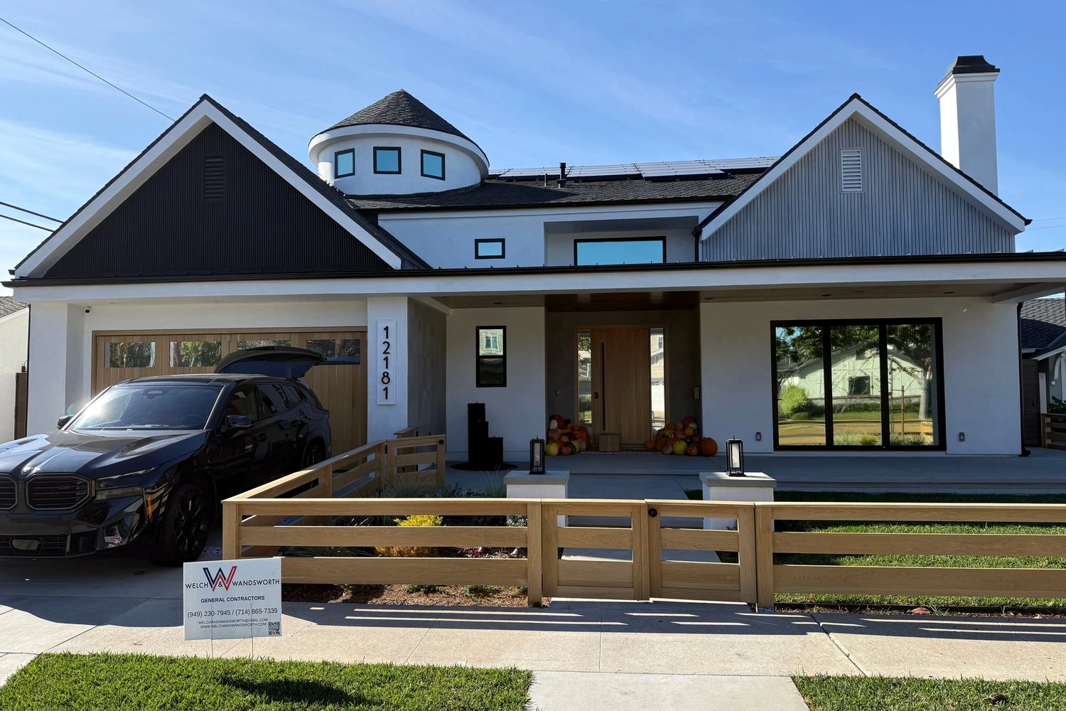The finished house from the same spot, standing seam metal roof, stucco and board cladding