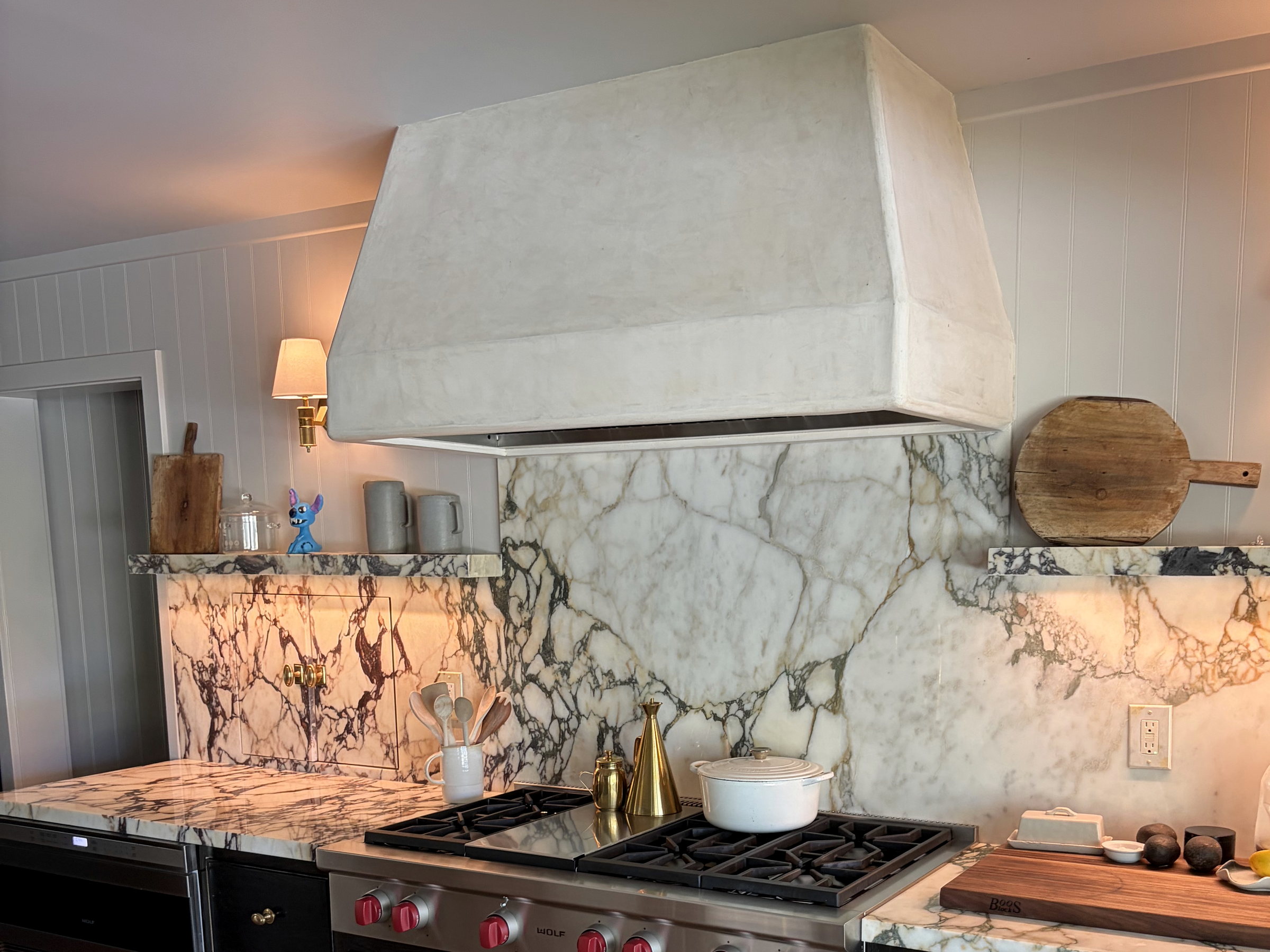 A plaster hood over the range, with marble carried from the counter to the ceiling behind it