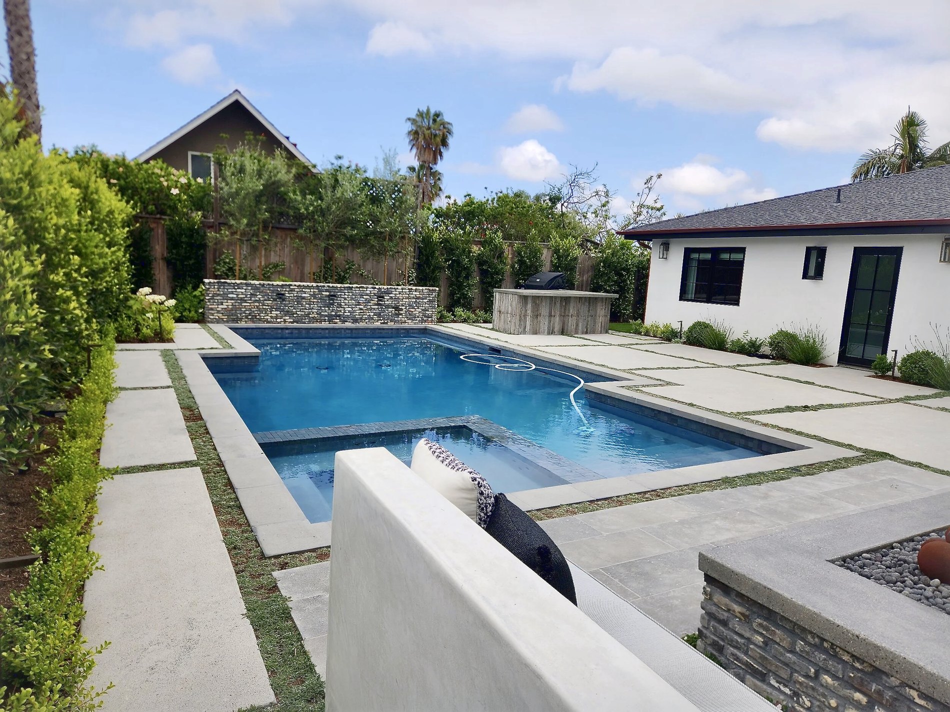 The rebuilt rear yard, pool and spa set into stone paving with the house alongside
