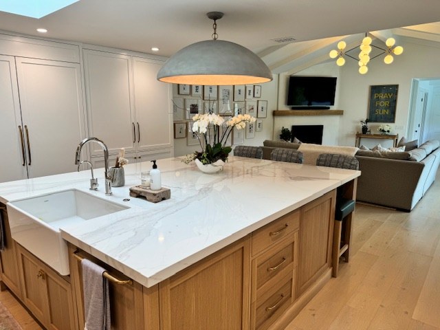 The remodeled kitchen, a marble island with a farmhouse sink and oak cabinetry, open to the living room.