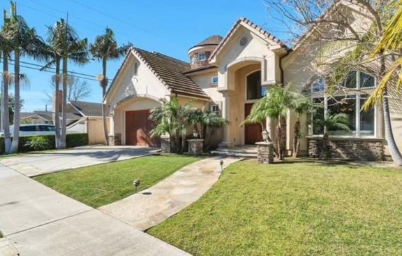 The front of the house before the phase two elevation work, a tile roof and palms over the lawn.