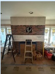 The brick fireplace during the remodel, ladders and drop cloths still in the room.