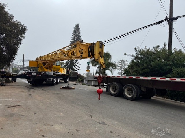 The crane set up in the street beside the flatbed carrying the container pool.