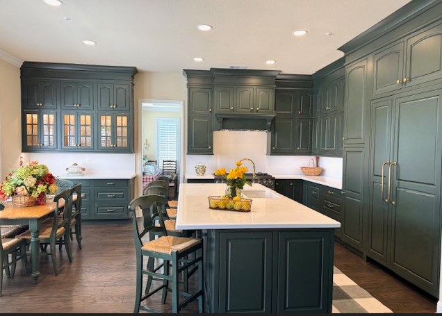 The kitchen in dark green Omega cabinetry, glazed upper doors above the run.
