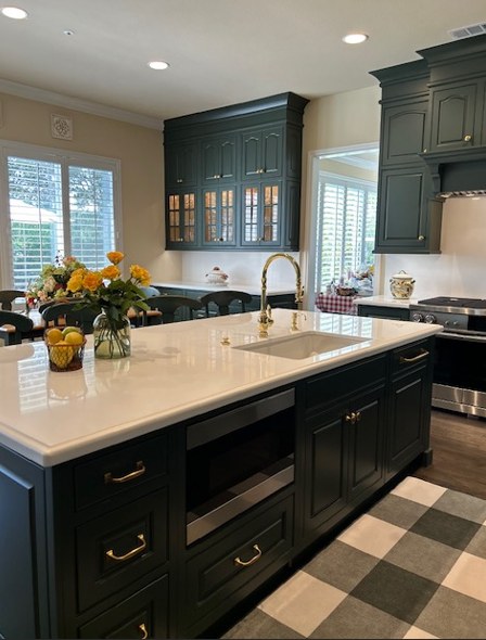 The island in white quartz with a brass faucet, over a checkerboard floor.