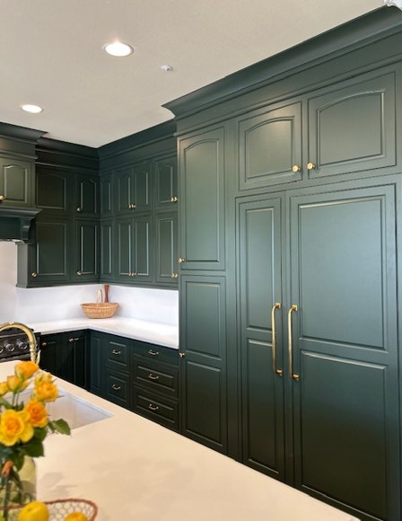 Floor to ceiling green cabinetry, with the refrigerator paneled to match.