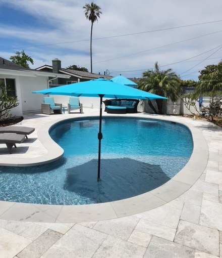 The finished pool in travertine, with the umbrella and loungers set out.