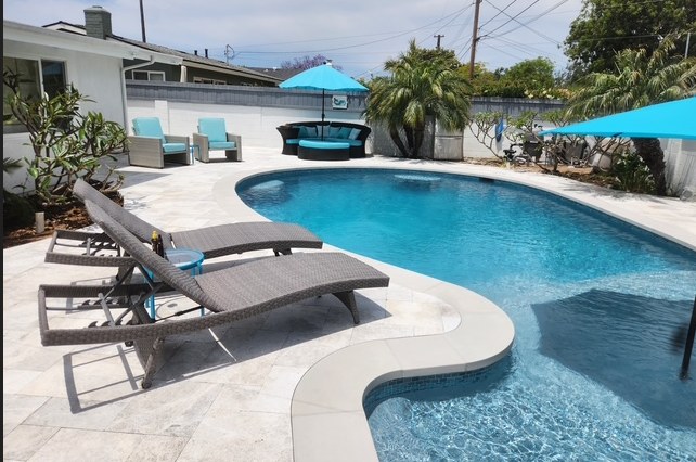 The finished pool and deck seen from the house, shade sails over the loungers.