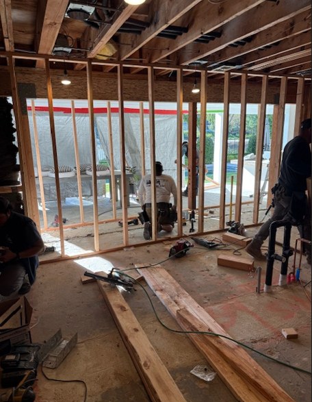 The framing opened up during the kitchen build, the crew working at the new wall.