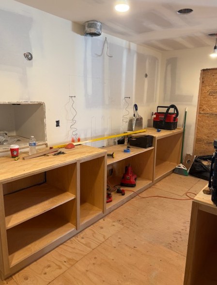 Cabinet boxes going in against fresh drywall.