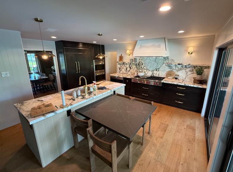 The finished kitchen, dark cabinetry and a marble slab behind the range.