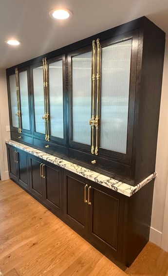 The tall glazed dresser in fluted glass and brass, on its marble counter.