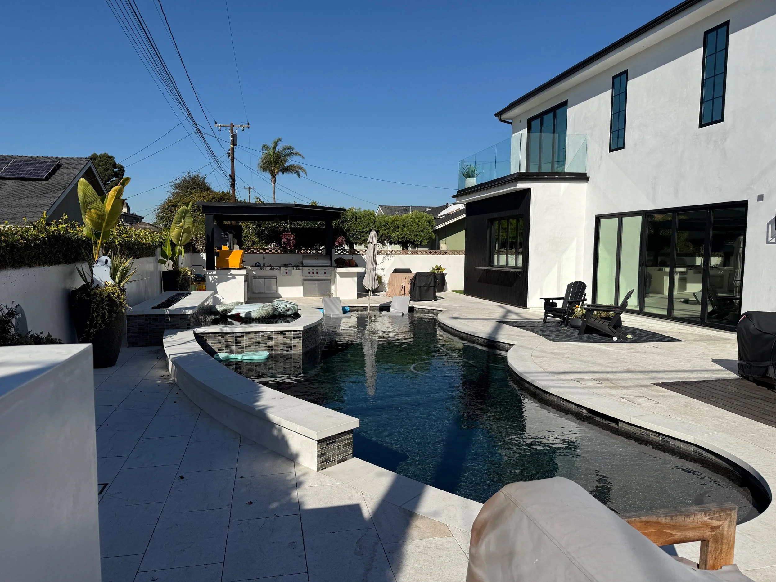 The finished Los Alamitos house from the garden, the pool and spa in the foreground and the outdoor kitchen under its pergola beyond