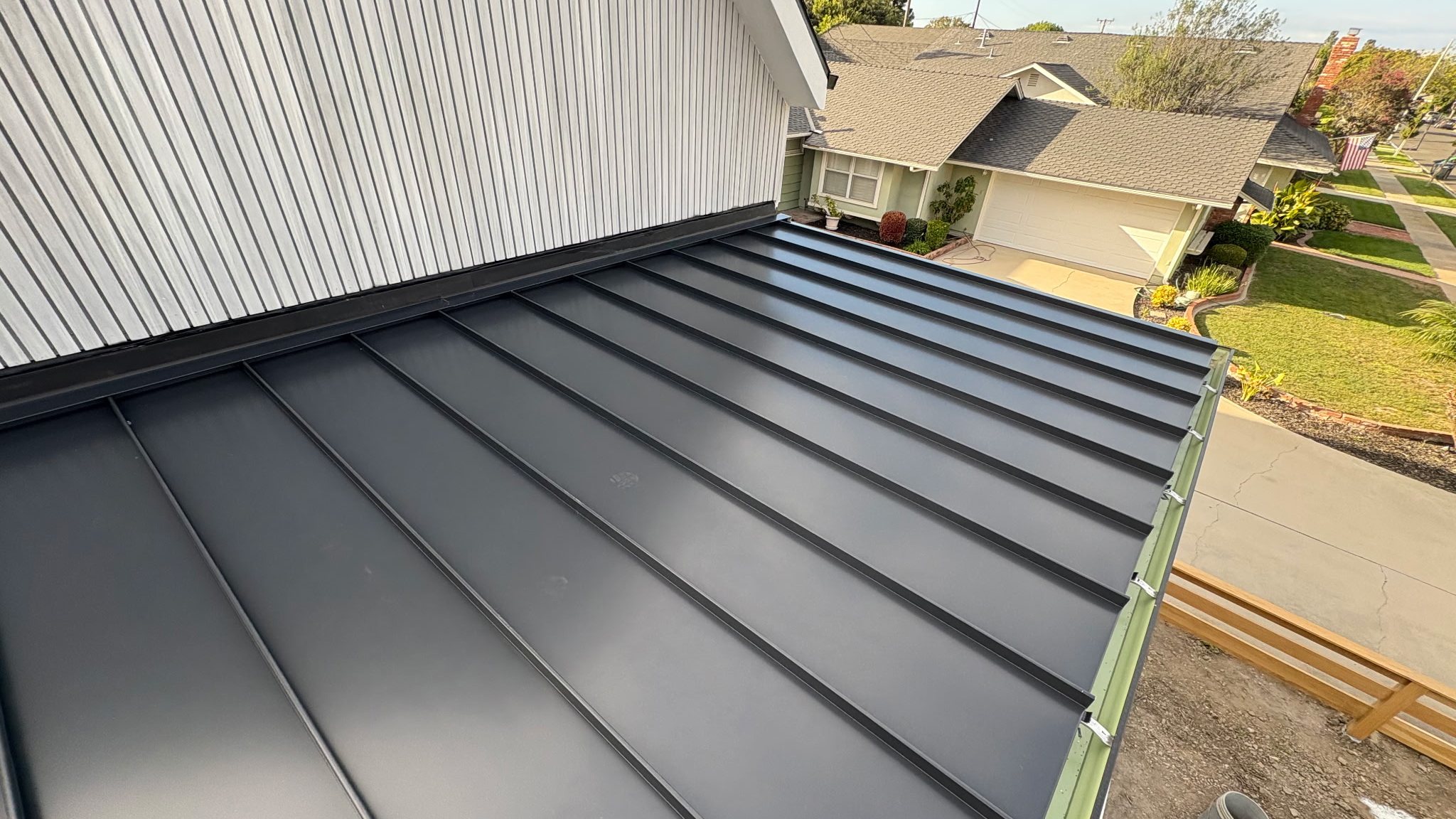A standing seam roof going down over new framing, clips visible along the eave