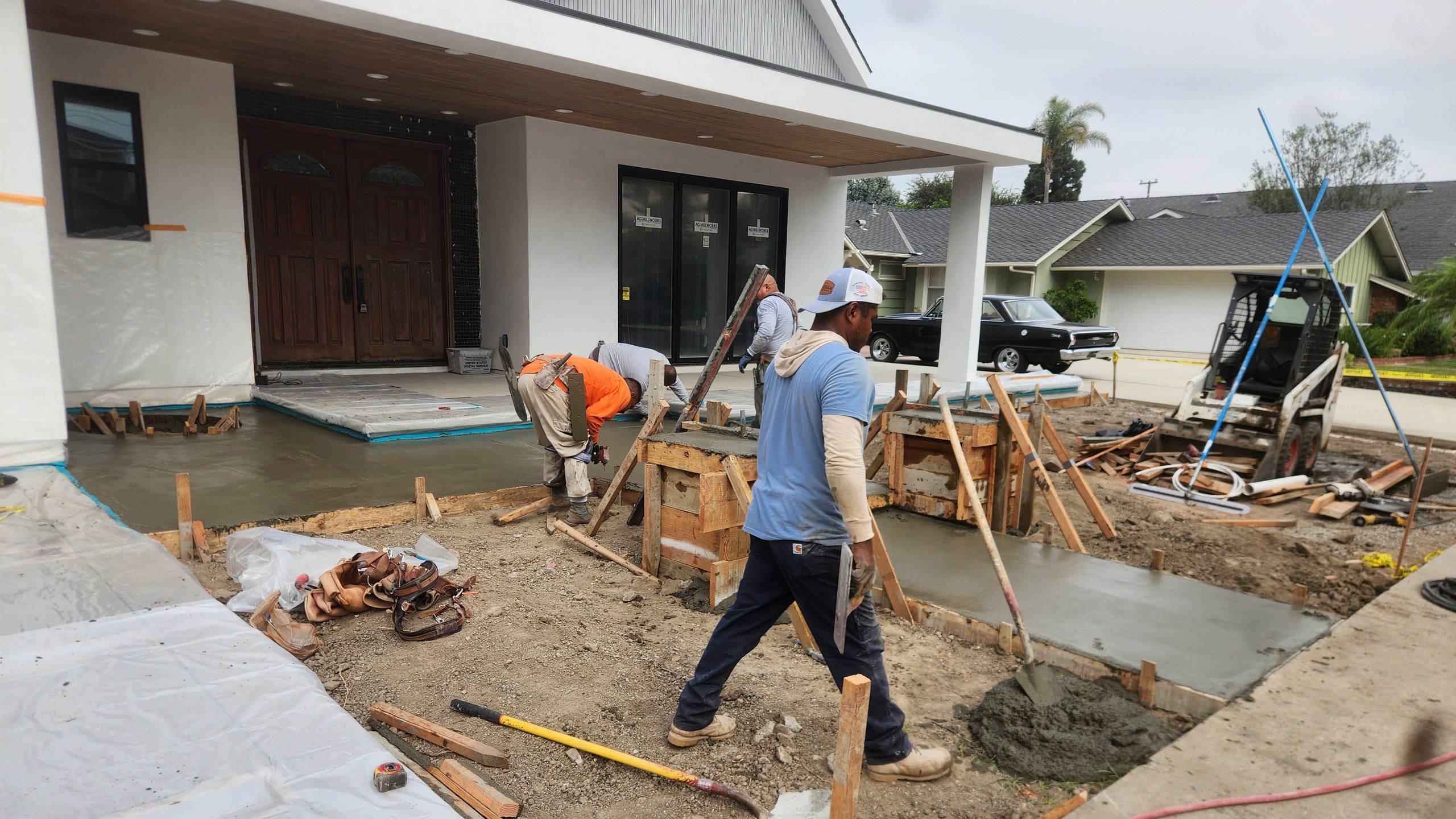 Two of the crew forming and finishing the entry hardscape at a Los Alamitos house, the finished elevation behind them